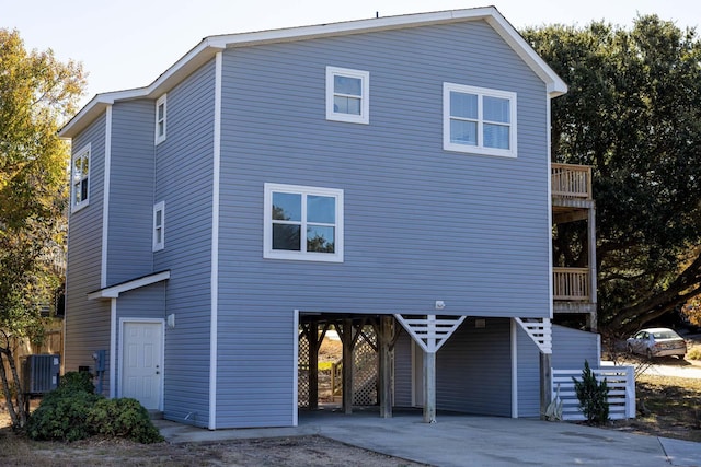 back of property featuring central air condition unit, a balcony, a carport, and concrete driveway