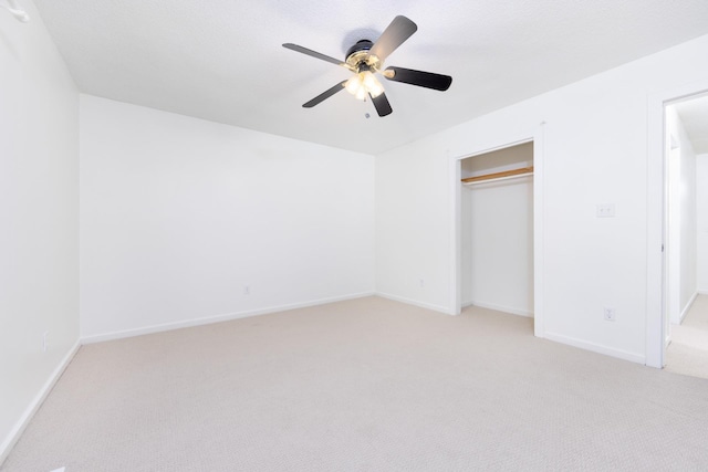 unfurnished bedroom with light carpet, ceiling fan, a closet, and baseboards