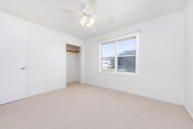 unfurnished bedroom with light colored carpet, a closet, visible vents, and baseboards