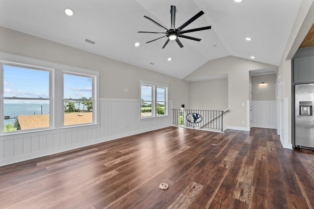 unfurnished living room with a wainscoted wall, a water view, dark wood finished floors, and visible vents