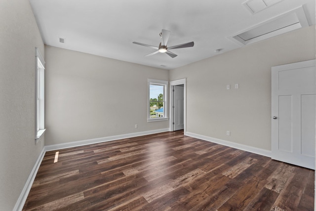 empty room featuring dark wood-style floors, visible vents, attic access, and baseboards