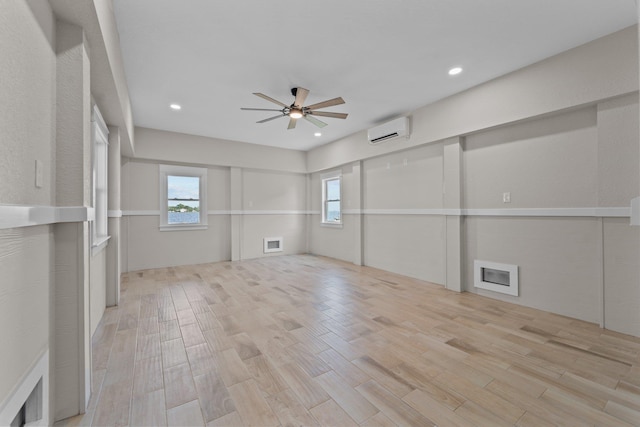 unfurnished room with an AC wall unit, light wood finished floors, a ceiling fan, and recessed lighting