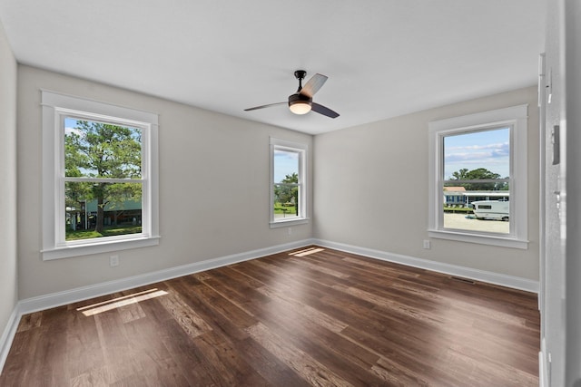 empty room featuring visible vents, baseboards, and dark wood-style flooring