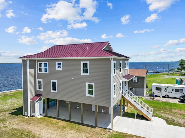 rear view of property with metal roof, a standing seam roof, and a water view