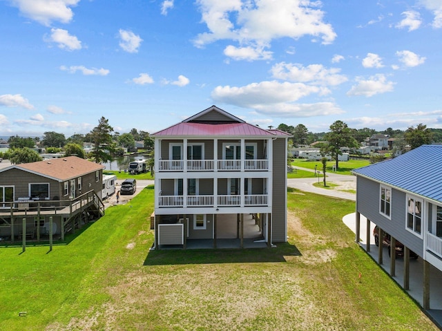 back of property featuring metal roof, a lawn, and a balcony