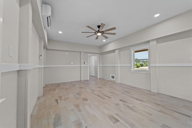 unfurnished room with light wood-type flooring, visible vents, a ceiling fan, and a wall mounted AC