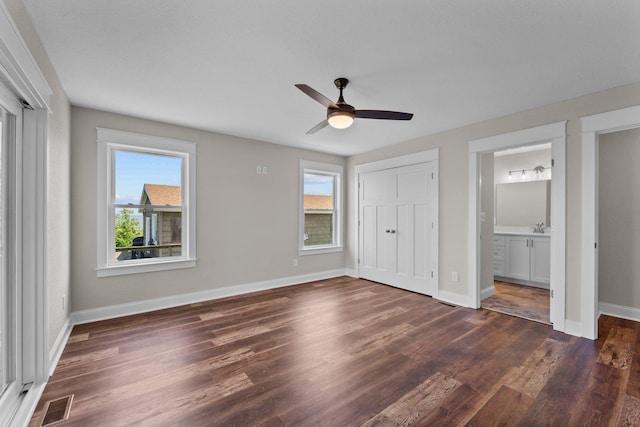 unfurnished bedroom with baseboards, multiple windows, visible vents, and dark wood-style flooring