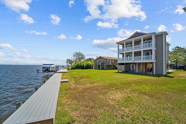 view of dock with a water view, a balcony, and a lawn