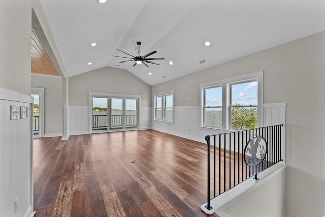 unfurnished living room featuring dark wood-type flooring, lofted ceiling, wainscoting, and recessed lighting