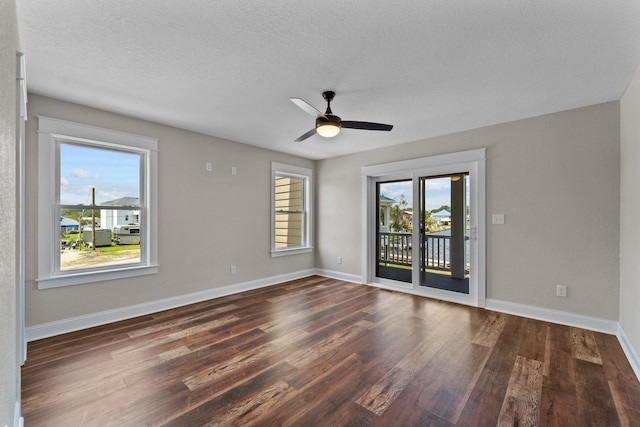 spare room with plenty of natural light, baseboards, and dark wood-type flooring