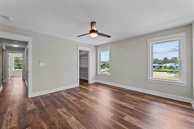 spare room featuring a ceiling fan, a textured ceiling, baseboards, and dark wood-type flooring