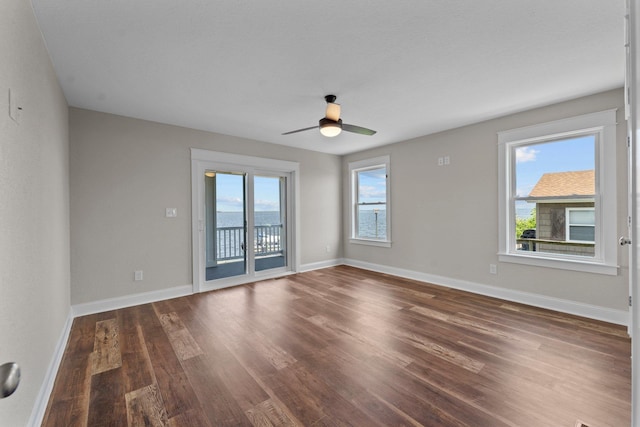 unfurnished room featuring dark wood-style floors, a ceiling fan, and baseboards