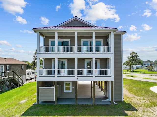 back of house featuring a yard, a patio, a standing seam roof, metal roof, and a carport