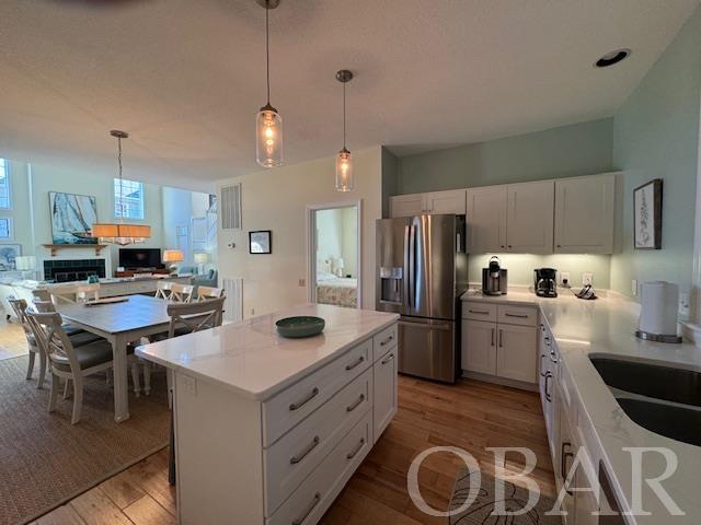 kitchen featuring light countertops, a kitchen island, stainless steel refrigerator with ice dispenser, and white cabinetry