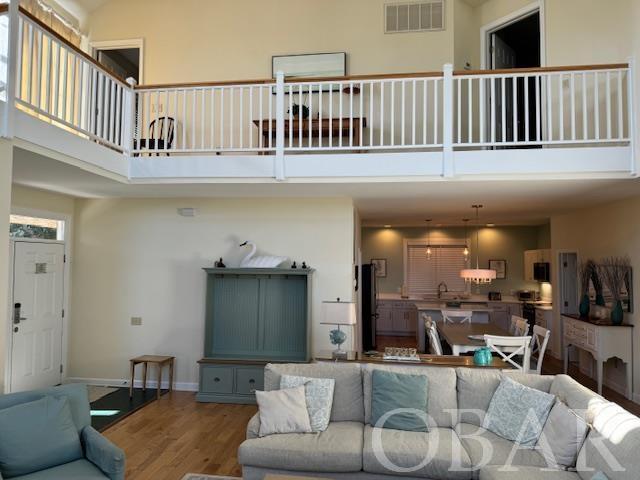 living room with baseboards, a high ceiling, visible vents, and wood finished floors