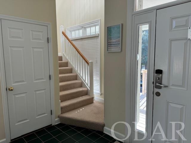 entrance foyer featuring stairs, dark tile patterned flooring, and baseboards