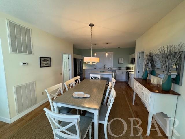 dining area with dark wood-style flooring, visible vents, and baseboards