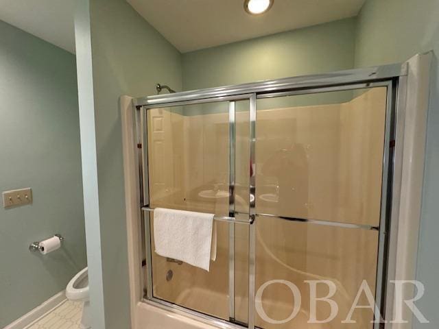 bathroom with toilet, baseboards, and bath / shower combo with glass door