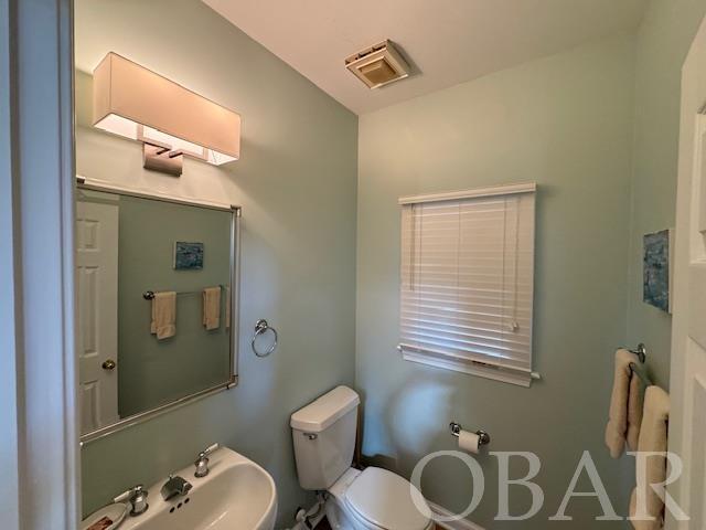 half bathroom with toilet, visible vents, and a sink