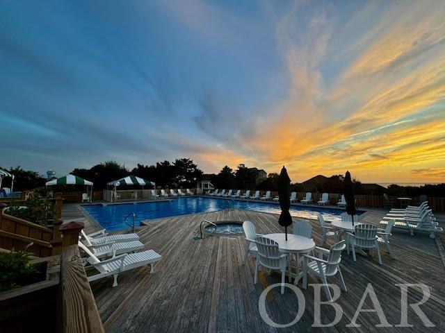 pool at dusk with a deck and a community pool