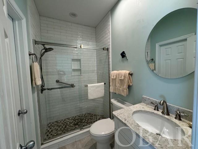 full bath with toilet, a stall shower, and vanity