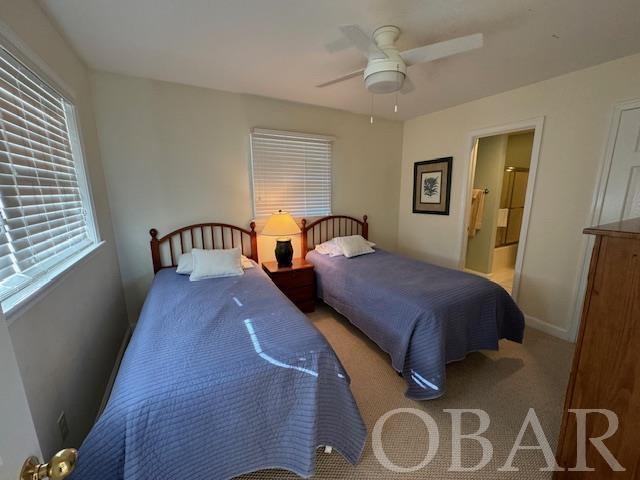 bedroom featuring a ceiling fan, light colored carpet, connected bathroom, and baseboards