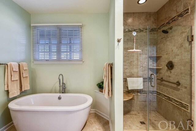 bathroom featuring a freestanding bath, a shower stall, and baseboards