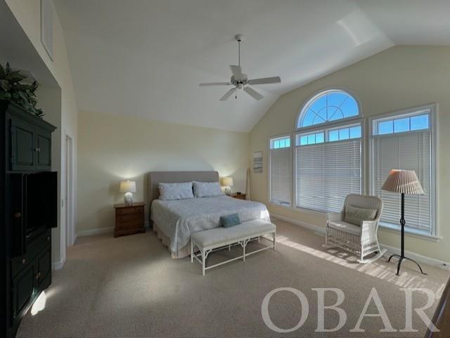 carpeted bedroom featuring lofted ceiling, baseboards, and a ceiling fan