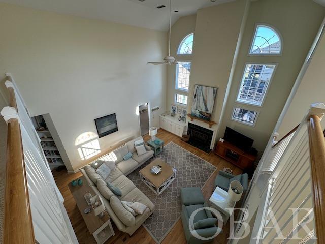 living room featuring high vaulted ceiling, a fireplace, wood finished floors, and a ceiling fan