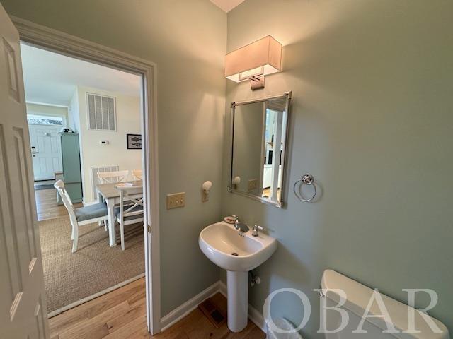 bathroom with baseboards, visible vents, toilet, wood finished floors, and a sink