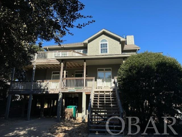 beach home featuring a carport, covered porch, driveway, and stairway