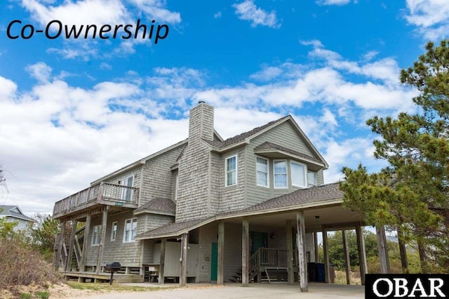 exterior space with a carport, a shingled roof, a chimney, and a balcony