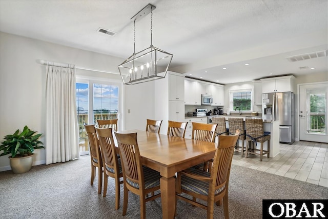 dining area with light carpet, plenty of natural light, and visible vents