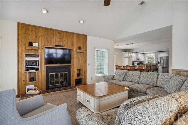 carpeted living area featuring visible vents, a tile fireplace, vaulted ceiling, wood walls, and recessed lighting