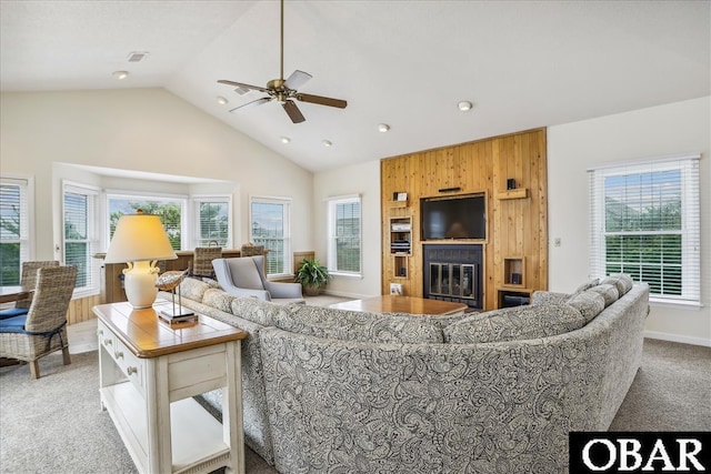 living area with light colored carpet, visible vents, a ceiling fan, a large fireplace, and high vaulted ceiling