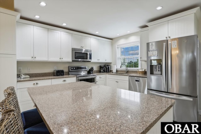 kitchen featuring a sink, appliances with stainless steel finishes, a kitchen island, and white cabinetry