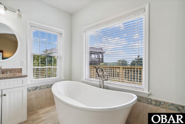 full bathroom with a soaking tub and vanity