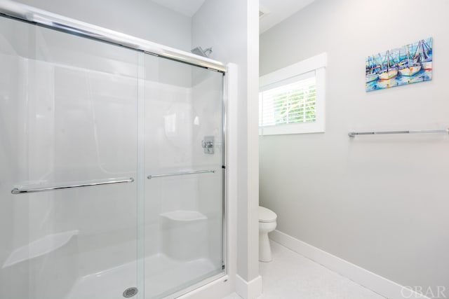 bathroom featuring toilet, a stall shower, and baseboards