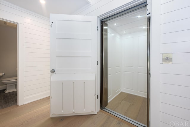 bathroom with toilet, wood walls, and wood finished floors