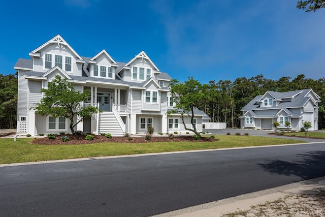 view of front of property featuring board and batten siding, a residential view, stairway, and a front lawn