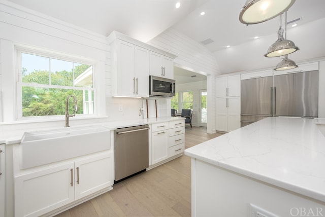 kitchen featuring stainless steel appliances, a sink, white cabinetry, and pendant lighting