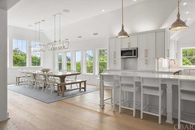 kitchen with light countertops, pendant lighting, stainless steel microwave, and white cabinetry