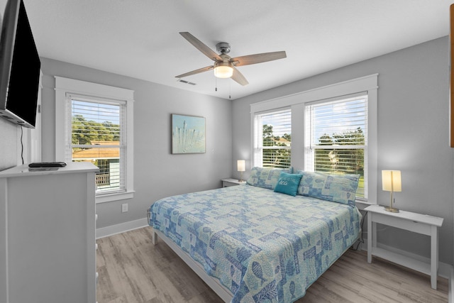 bedroom with light wood finished floors, baseboards, visible vents, and a ceiling fan