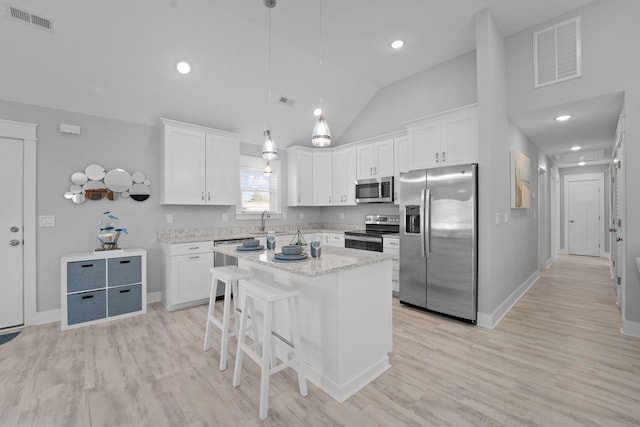 kitchen with visible vents, decorative light fixtures, a center island, stainless steel appliances, and white cabinetry