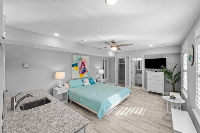 bedroom with recessed lighting, a sink, light wood-style flooring, and baseboards