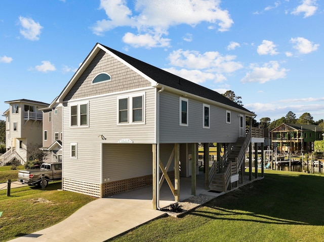 rear view of property featuring a carport, concrete driveway, a yard, and stairway