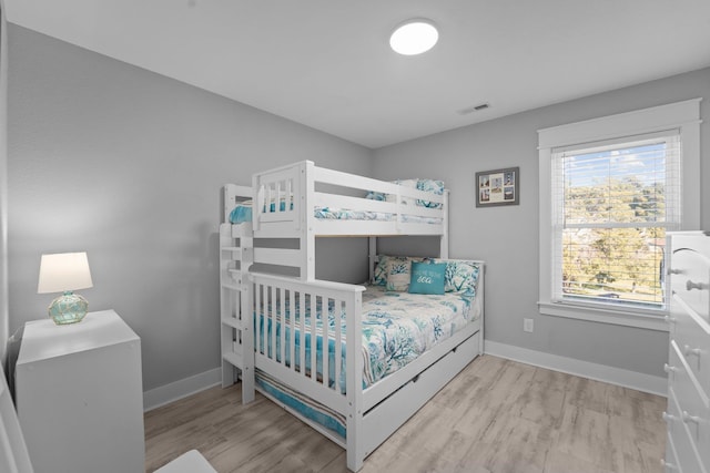 bedroom with baseboards, visible vents, and light wood-style floors