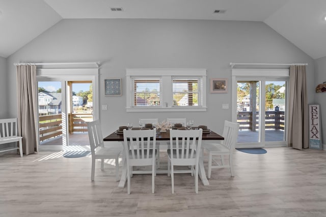 dining room featuring light wood-type flooring, lofted ceiling, and visible vents