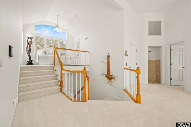 hall with baseboards, visible vents, high vaulted ceiling, carpet flooring, and an upstairs landing