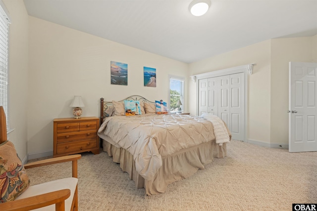 bedroom with baseboards, a closet, and light carpet